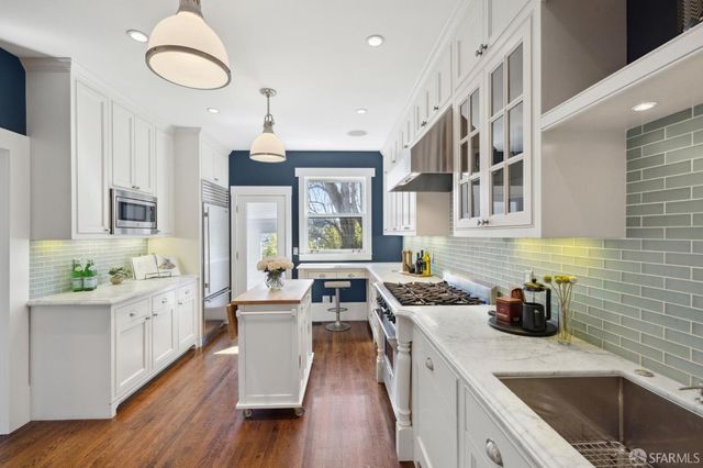 a kitchen with a sink stove cabinets and wooden floor