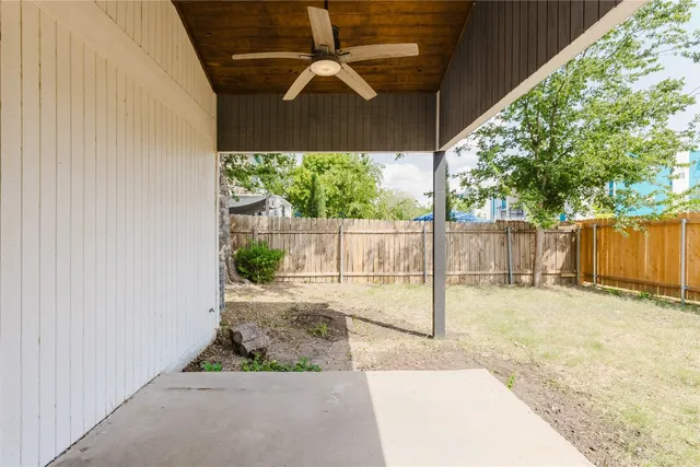 a backyard of a house with table and chairs under an umbrella with a small yard