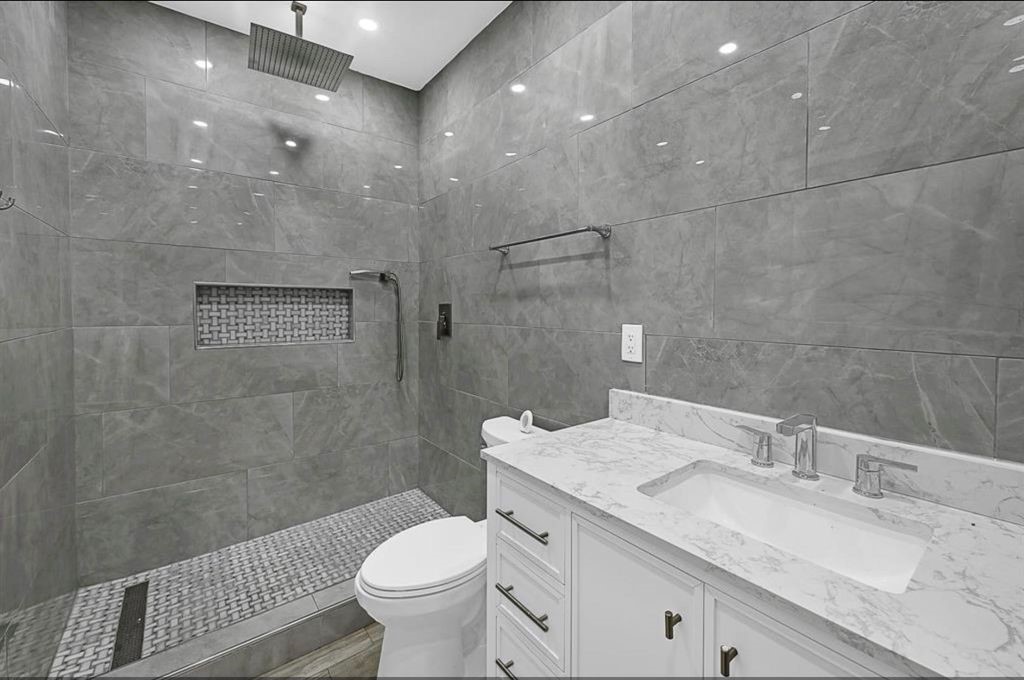 12430 Pecan Court Houston, TX 77013 - Photo 2 of 10 a bathroom with a granite countertop sink a toilet a mirror and shower