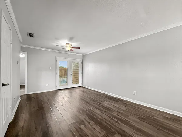 a view of an empty room with wooden floor and a window