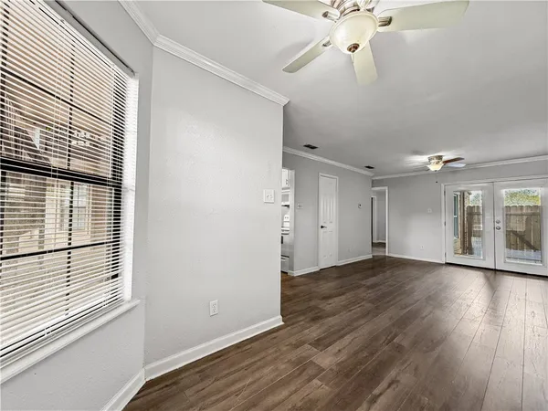 an empty room with wooden floor chandelier and windows