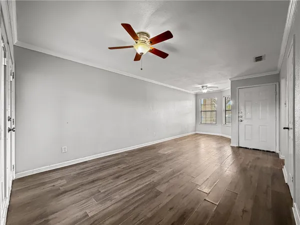 a view of an empty room with wooden floor and a ceiling fan