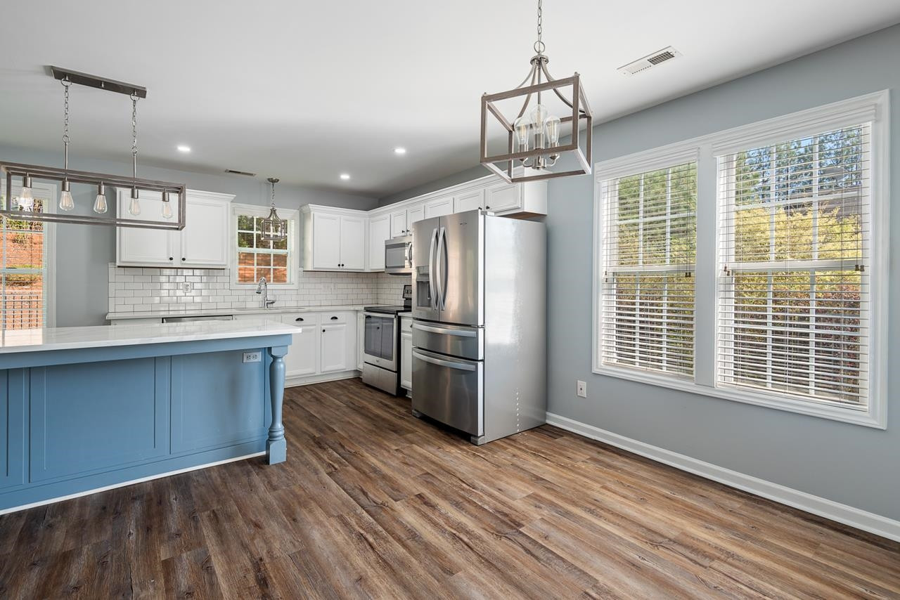 308 Saranac Ridge Drive Holly Springs, NC 27540 - Photo 11 of 41 a kitchen with stainless steel appliances granite countertop a refrigerator a sink dishwasher a stove and white countertops with wooden floor