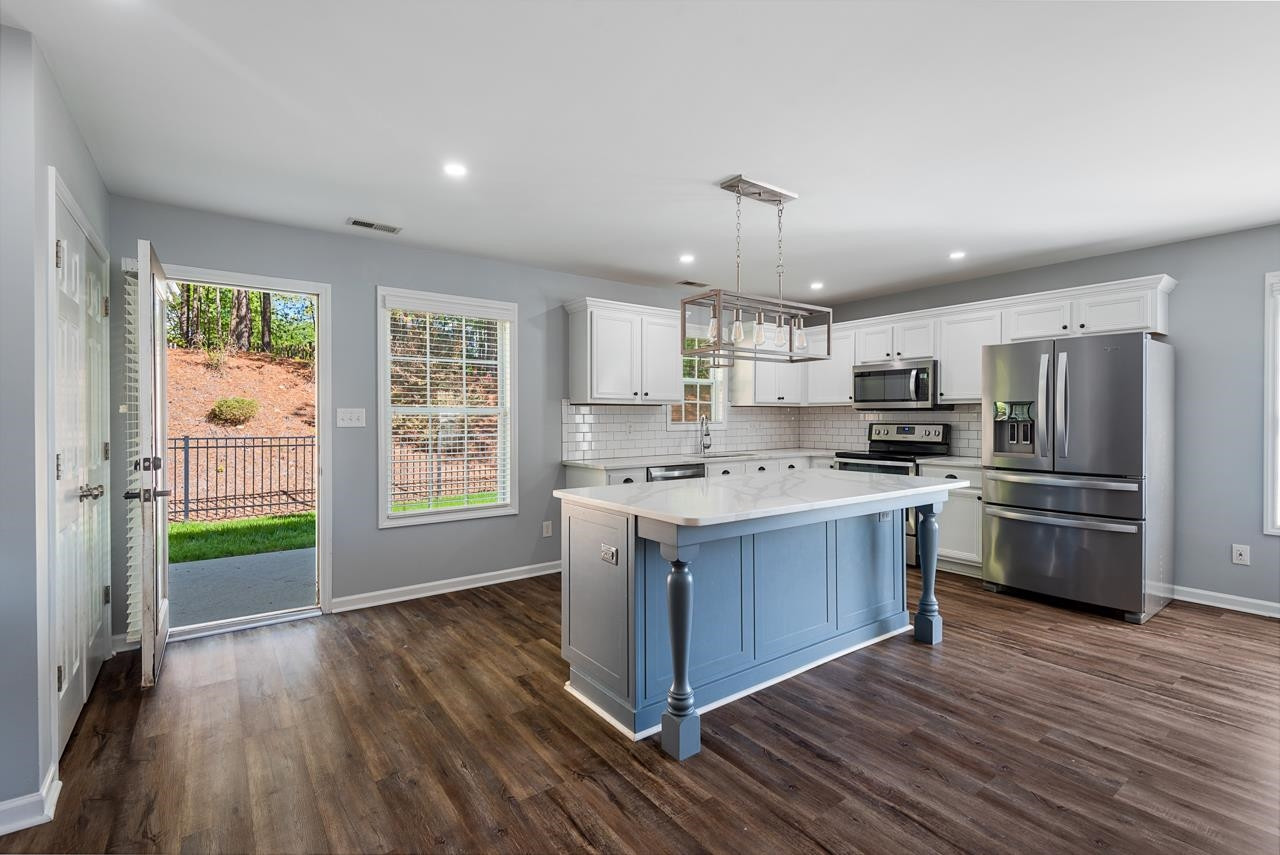 308 Saranac Ridge Drive Holly Springs, NC 27540 - Photo 16 of 41 a kitchen with stainless steel appliances kitchen island granite countertop a refrigerator a sink dishwasher a stove and a dining table with wooden floor