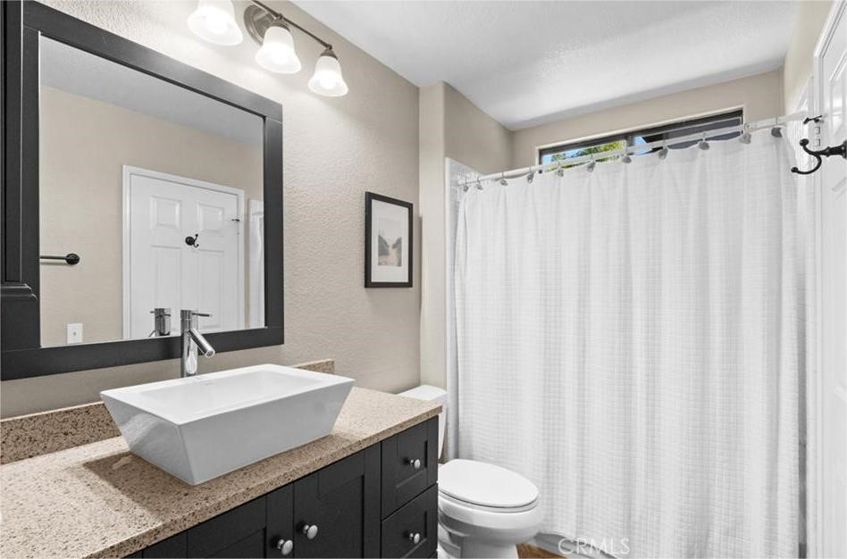 42050 Humber Drive Temecula, CA 92591 - Photo 22 of 31 a bathroom with a sink toilet a mirror and shower curtain