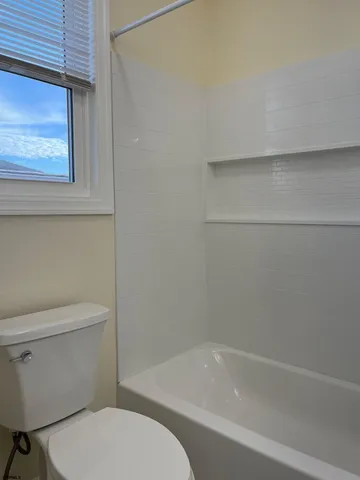 a white toilet sitting next to a bath tub