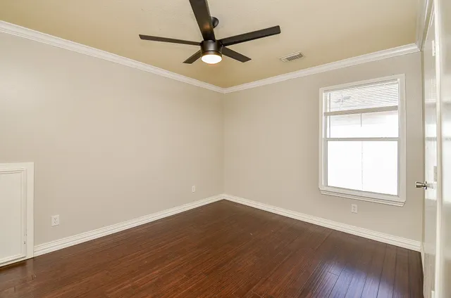 an empty room with wooden floor fan and windows