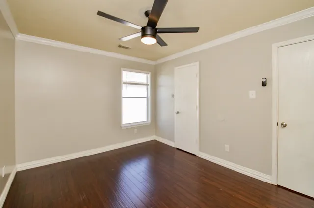 an empty room with wooden floor fan and windows