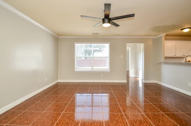 a view of an empty room with window and chandelier fan