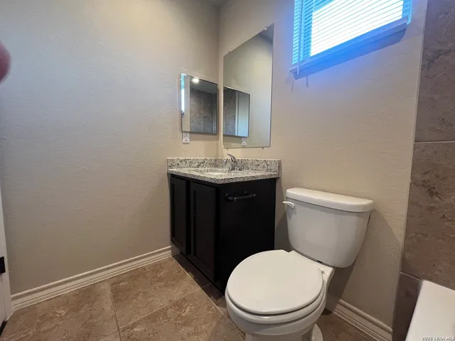a bathroom with a granite countertop toilet a sink and mirror