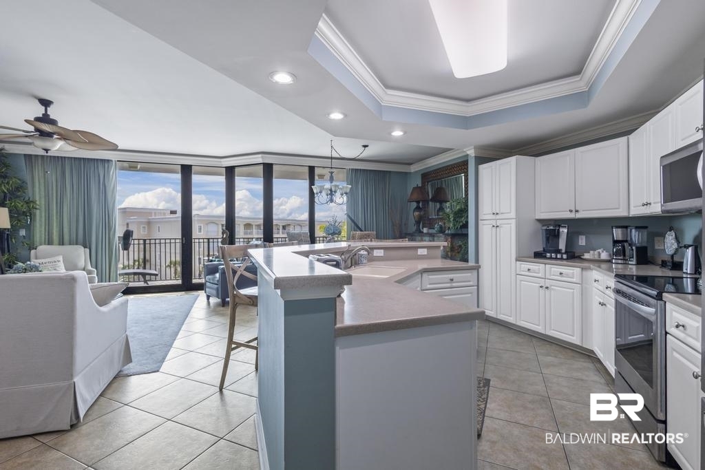 27582 Canal Road, Unit 2408 Orange Beach, AL 36561 - Photo 2 of 47 Kitchen featuring a center island with sink, appliances with stainless steel finishes, a tray ceiling, ceiling fan, and white cabinets