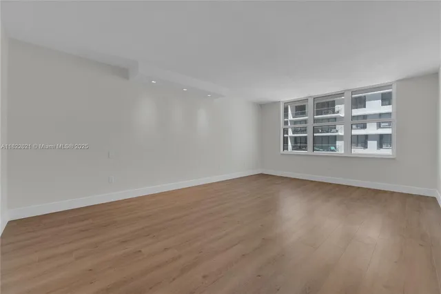 a view of an empty room with a window and wooden floor
