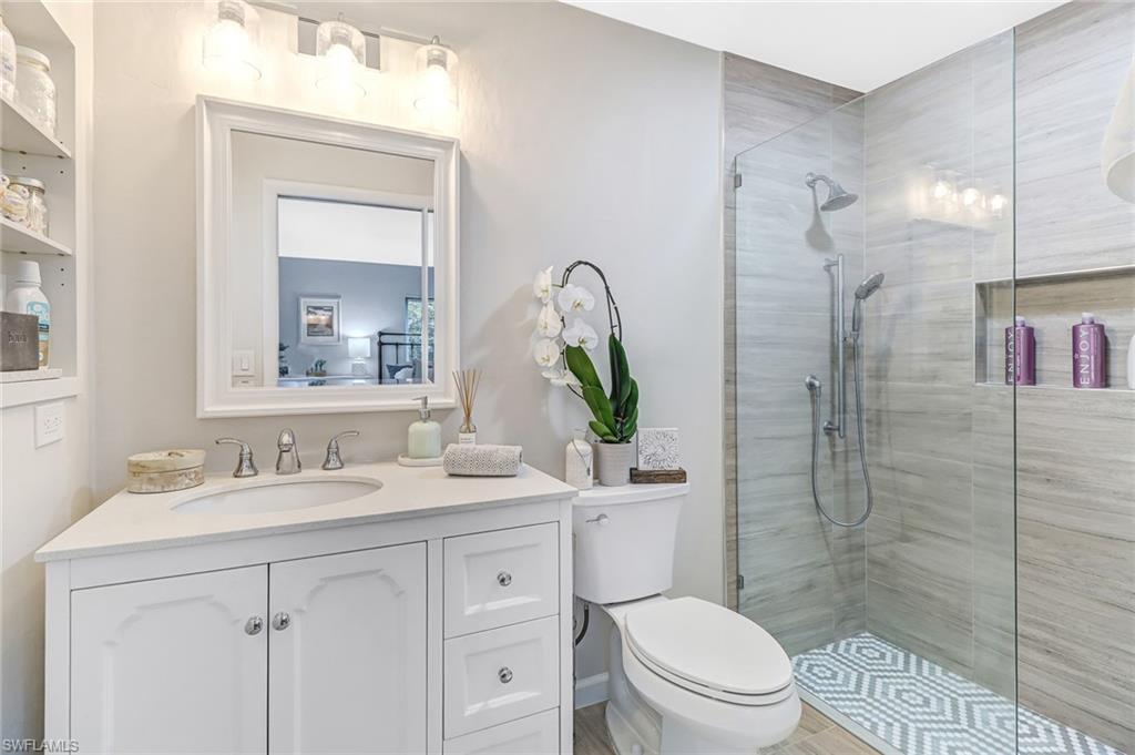 4576 Eagle Key Circle Naples, FL 34112 - Photo 8 of 18 a bathroom with a toilet a sink a glass door a shower and a mirror