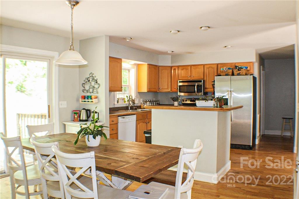 a room with stainless steel appliances kitchen island granite countertop a dining table chairs and granite counter tops