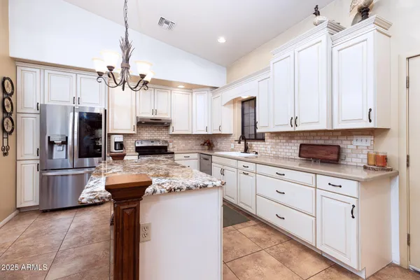 a kitchen with stainless steel appliances kitchen island granite countertop a refrigerator a sink dishwasher a stove and white cabinets with wooden floor