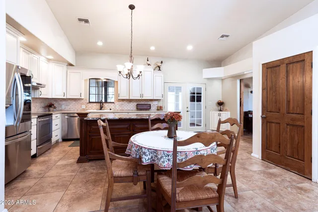 a view of a dining room and livingroom with furniture a chandelier and kitchen view