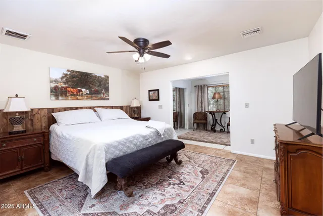 a spacious bedroom with a bed and a flat screen tv