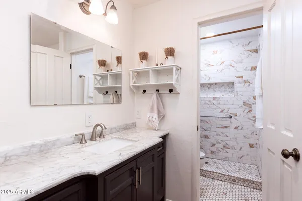 a bathroom with a granite countertop sink a mirror and shower