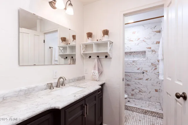 a bathroom with a granite countertop sink a mirror and shower