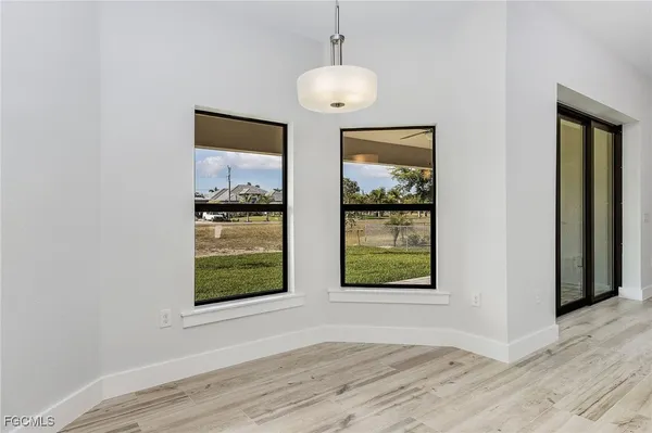 an empty room with wooden floor cabinet and windows