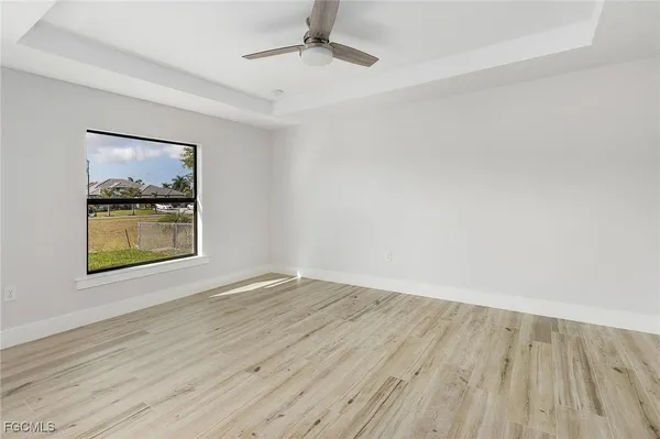 an empty room with wooden floor cabinet and windows