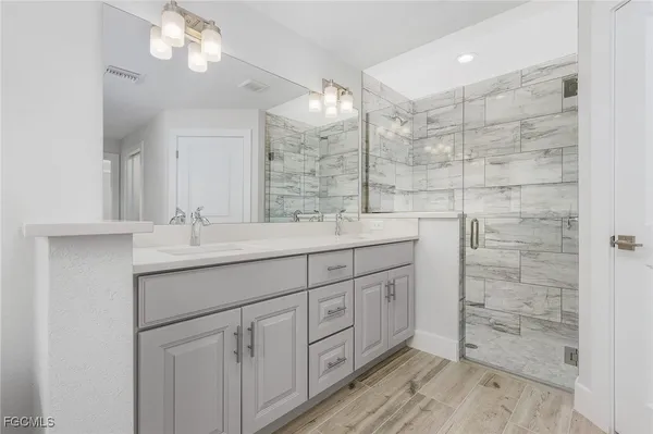 a bathroom with a double vanity sink mirror and shower