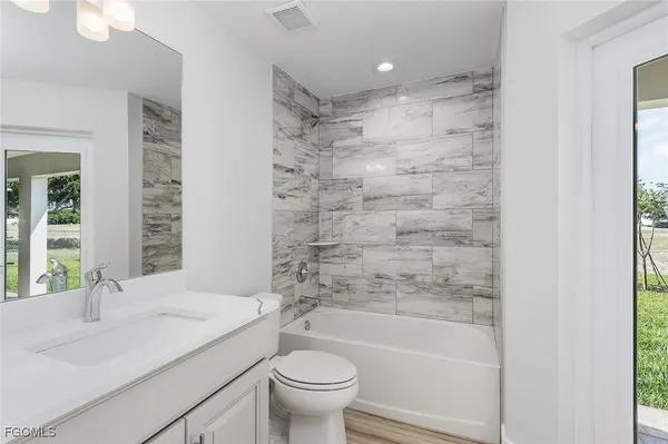 a bathroom with a granite countertop sink a toilet a mirror a bathtub and shower