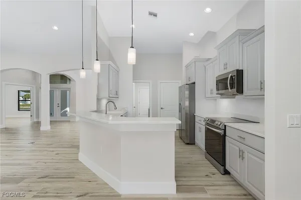 a large kitchen with stainless steel appliances kitchen island granite countertop a stove a sink and a refrigerator