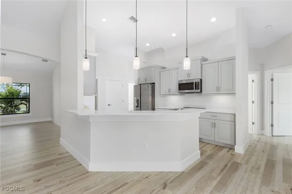 a large kitchen with stainless steel appliances sink refrigerator and wooden floor