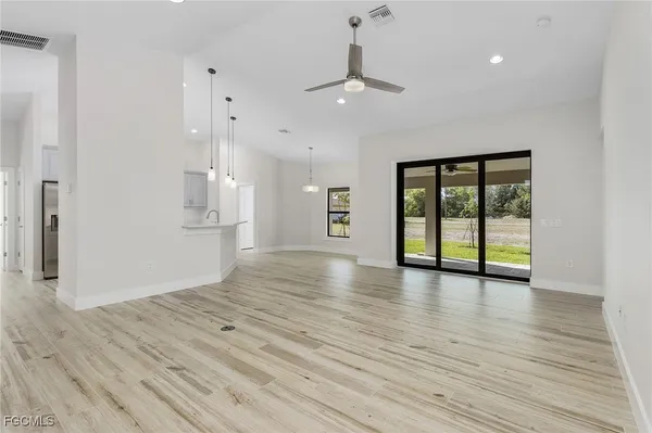 a view of an empty room with window and wooden floor