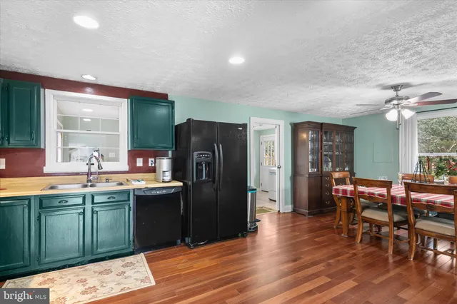 a kitchen with stainless steel appliances granite countertop a sink dishwasher and a refrigerator with wooden floor