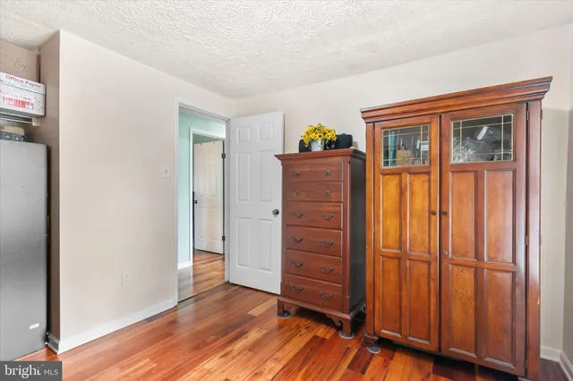 an empty room with wooden floor closet and windows