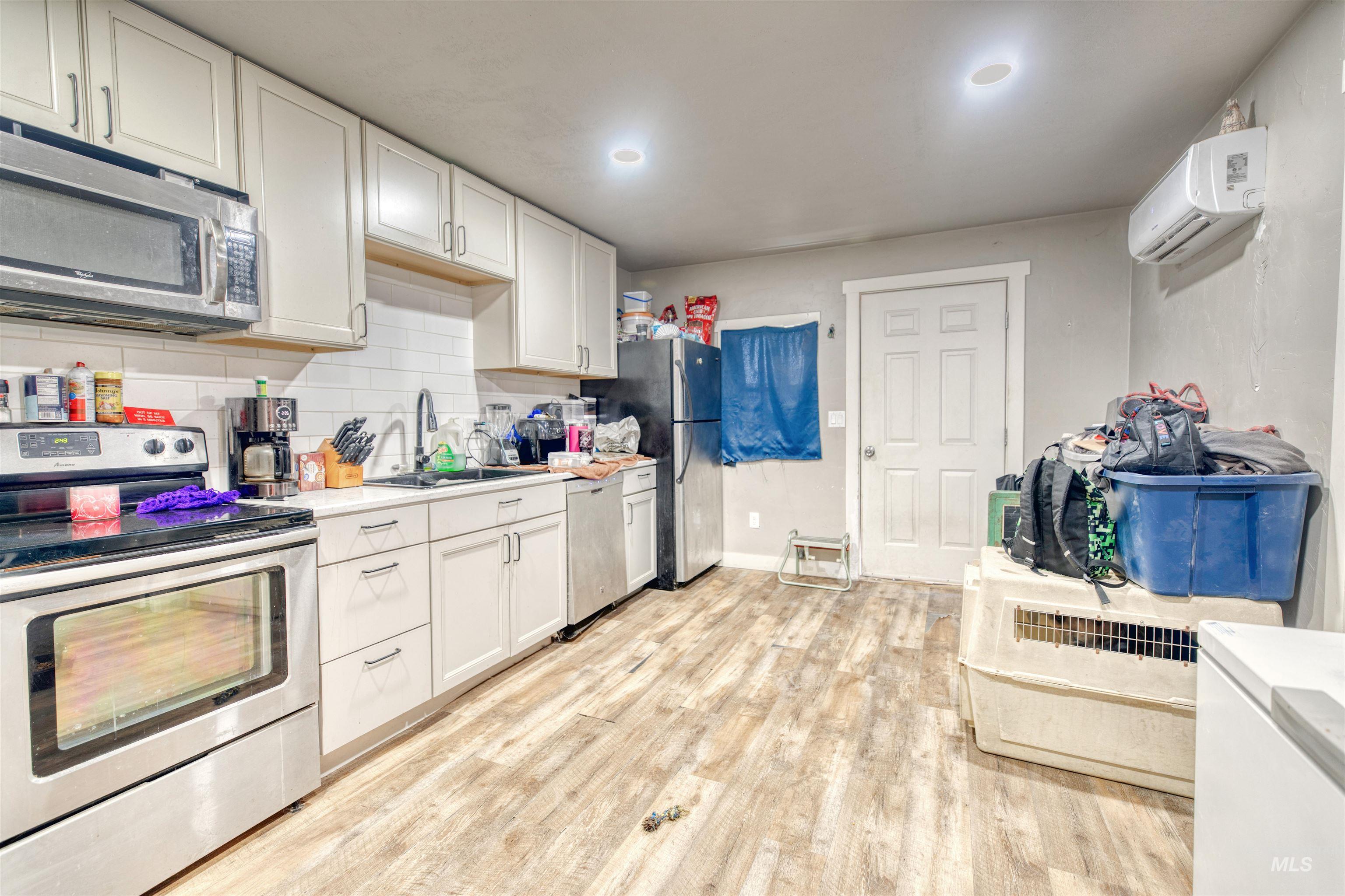 108 East Main Street Nyssa, OR 97913 - Photo 15 of 19 Kitchen featuring stainless steel appliances, a wall mounted air conditioner, light countertops, white cabinets, and recessed lighting