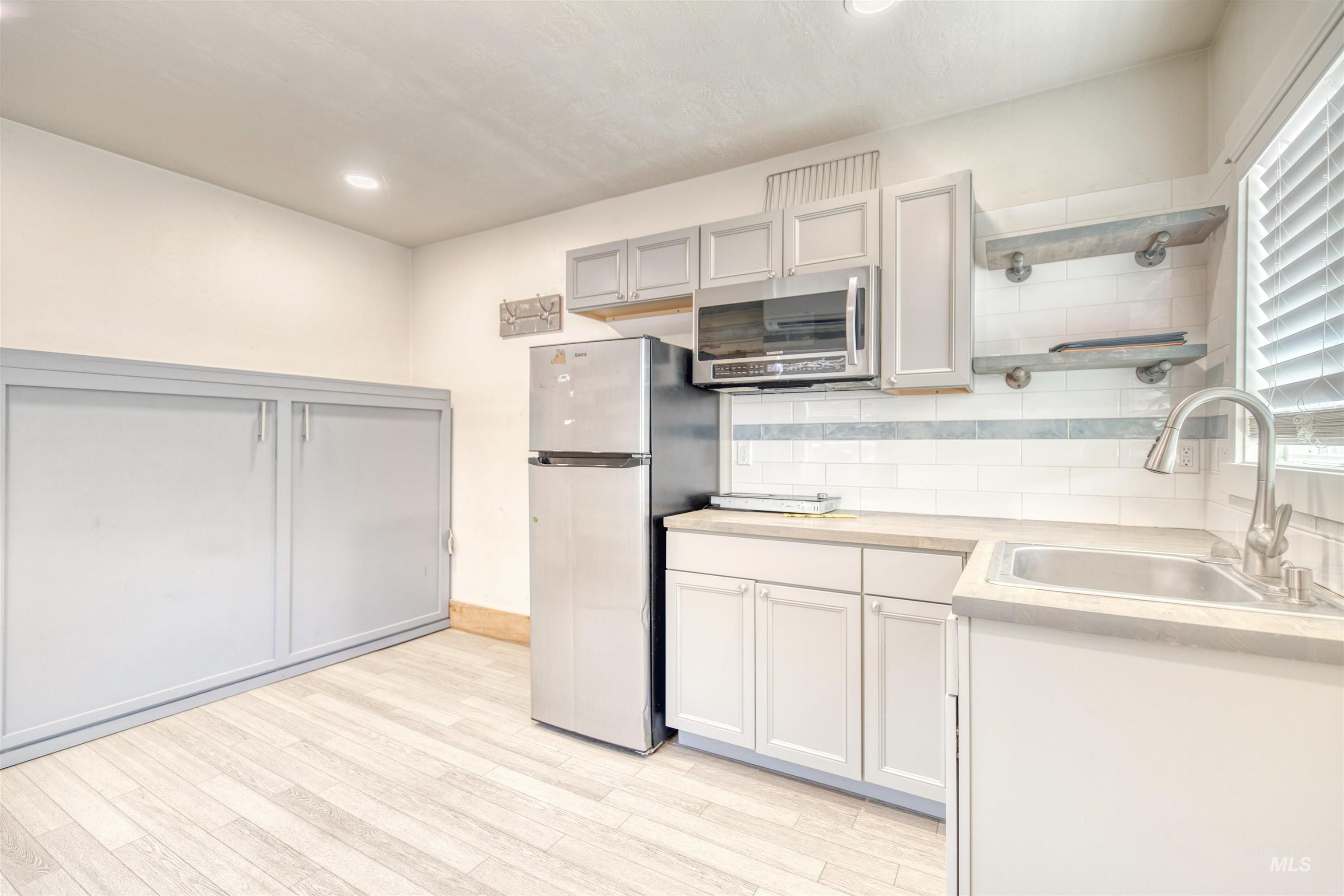 108 East Main Street Nyssa, OR 97913 - Photo 9 of 19 Kitchen with freestanding refrigerator, stainless steel microwave, open shelves, light wood-type flooring, and recessed lighting