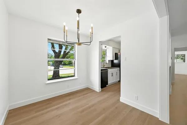 an empty room with wooden floor kitchen view and appliances