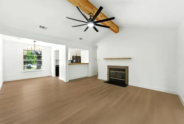a view of a livingroom with a fireplace a ceiling fan and windows