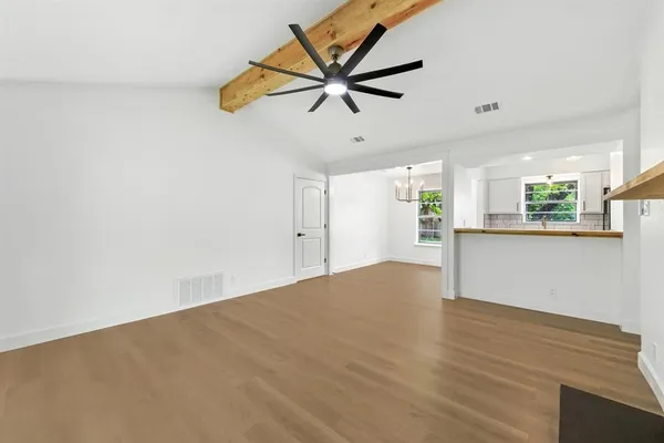 a view of an empty room with window and wooden floor