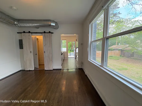 a view of an empty room with wooden floor and a window