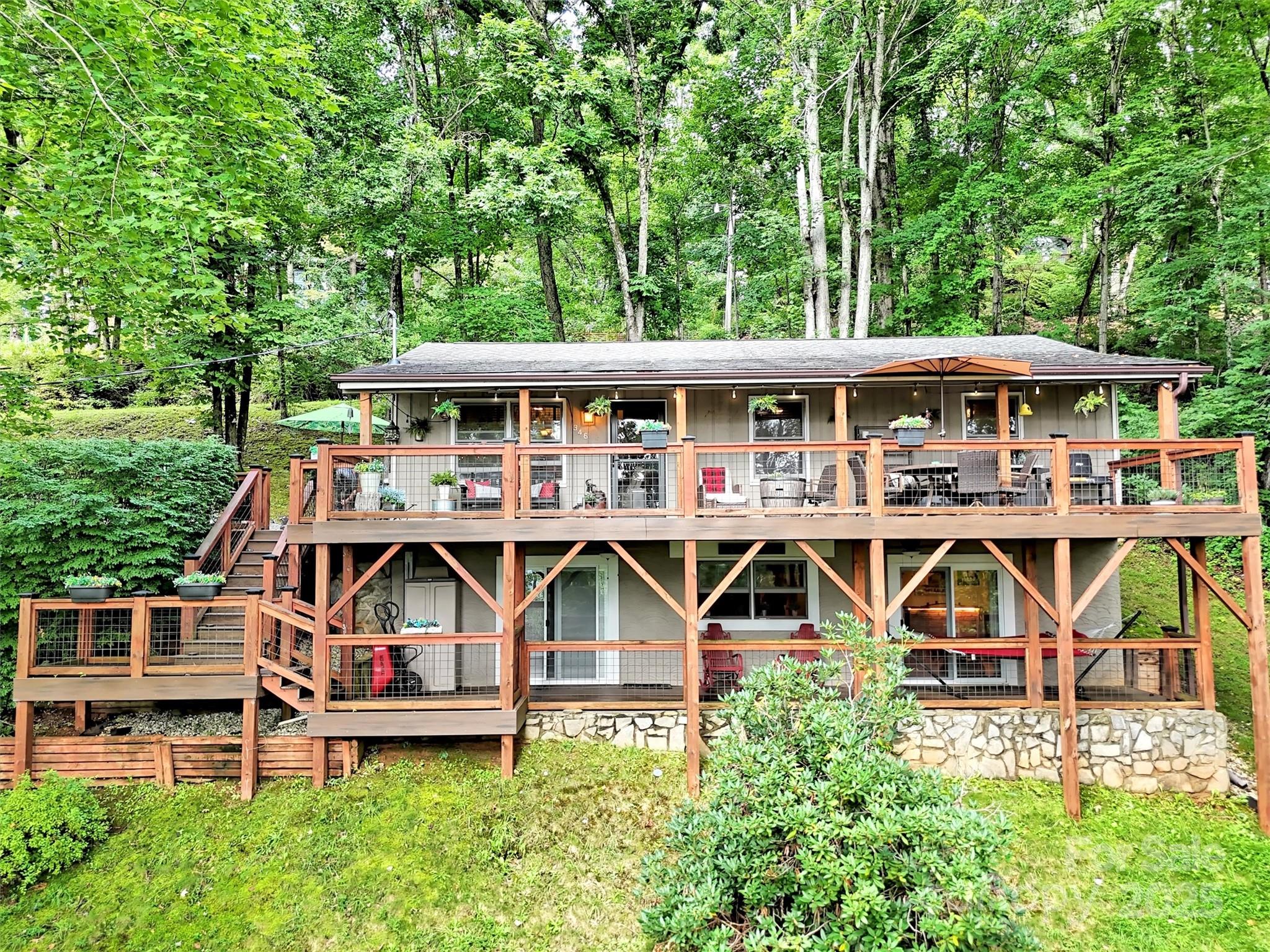 an aerial view of a house with wooden deck and furniture