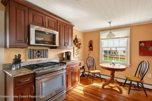 a kitchen with stainless steel appliances granite countertop a stove top oven a sink dishwasher a dining table and chairs with wooden floor
