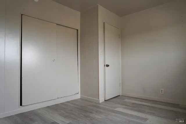 a view of an empty room with wooden floor and a bathroom