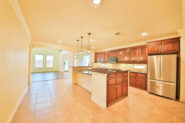 a kitchen with stainless steel appliances granite countertop a refrigerator a stove and a sink with wooden floor