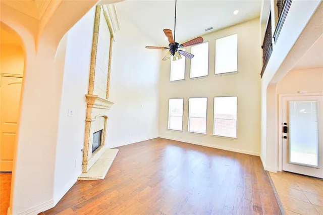 a view of an empty room with wooden floor and a fireplace