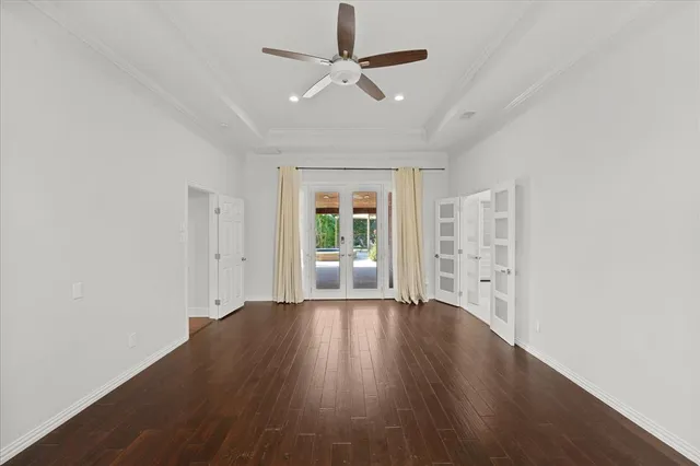 an empty room with wooden floor chandelier fan and windows