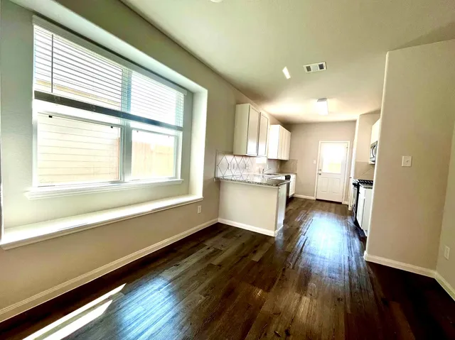 a view of a kitchen with wooden floor and a window
