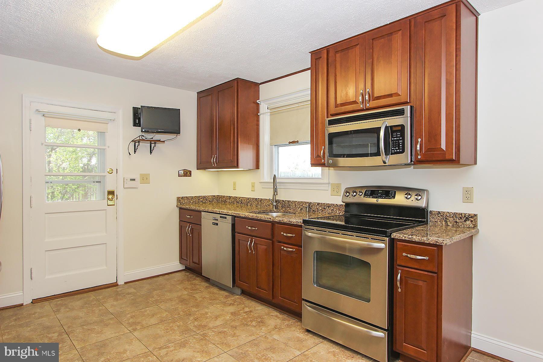 20820 Slidell Road Boyds, MD 20841 - Photo 8 of 29 a kitchen with granite countertop wooden cabinets stainless steel appliances and a sink