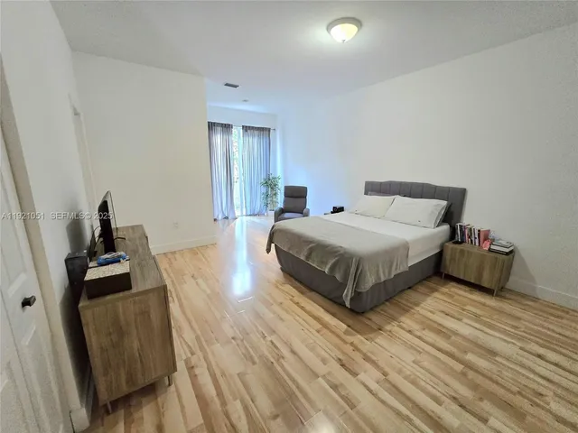 an empty room with wooden floor and a potted plant