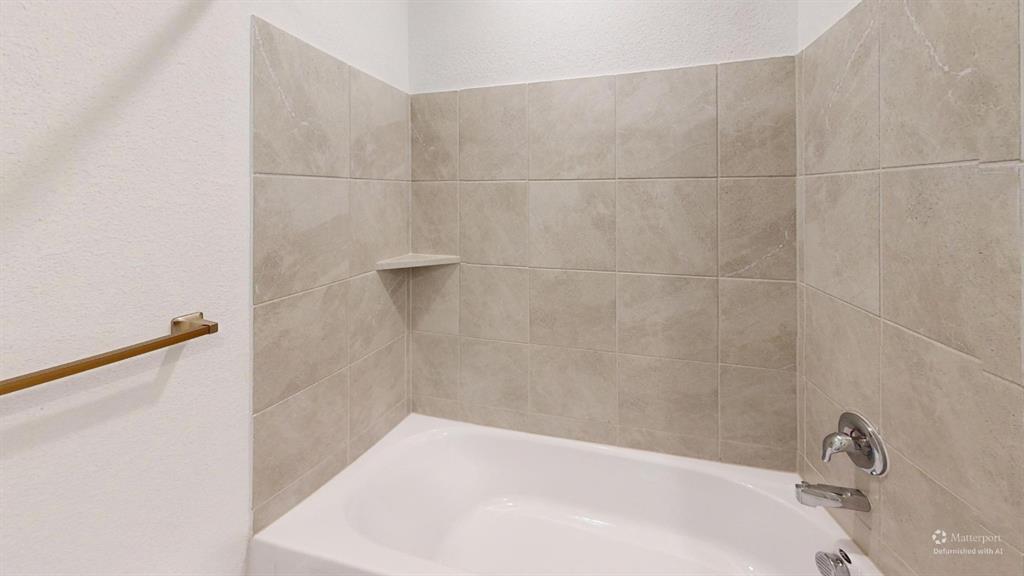 403 Ashbrook Way Princeton, TX 75407 - Photo 10 of 23 Bathtub with light-colored tile surround, integrated corner shelf, polished chrome fixtures, and a brass-tone towel bar