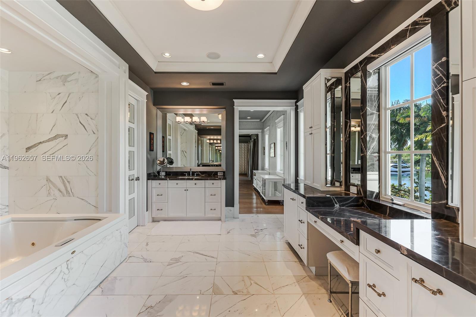 9320 Balada Street Coral Gables, FL 33156 - Photo 40 of 75 a large white bathroom with a granite countertop tub a sink and a large mirror