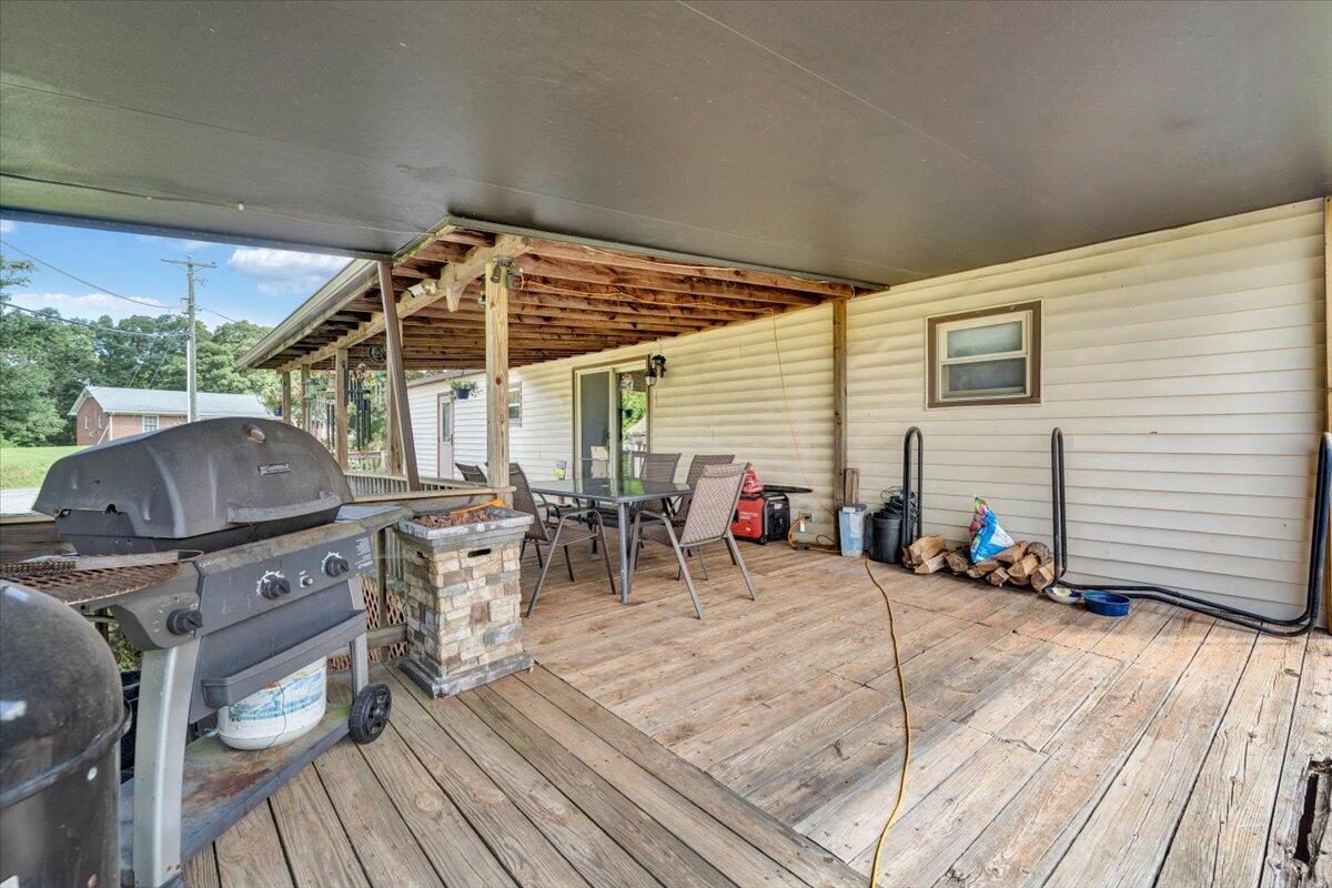 164 Tabernacle Road Penhook, VA 24137 - Photo 30 of 58 a view of a patio with table and chairs barbeque with wooden floor and fence